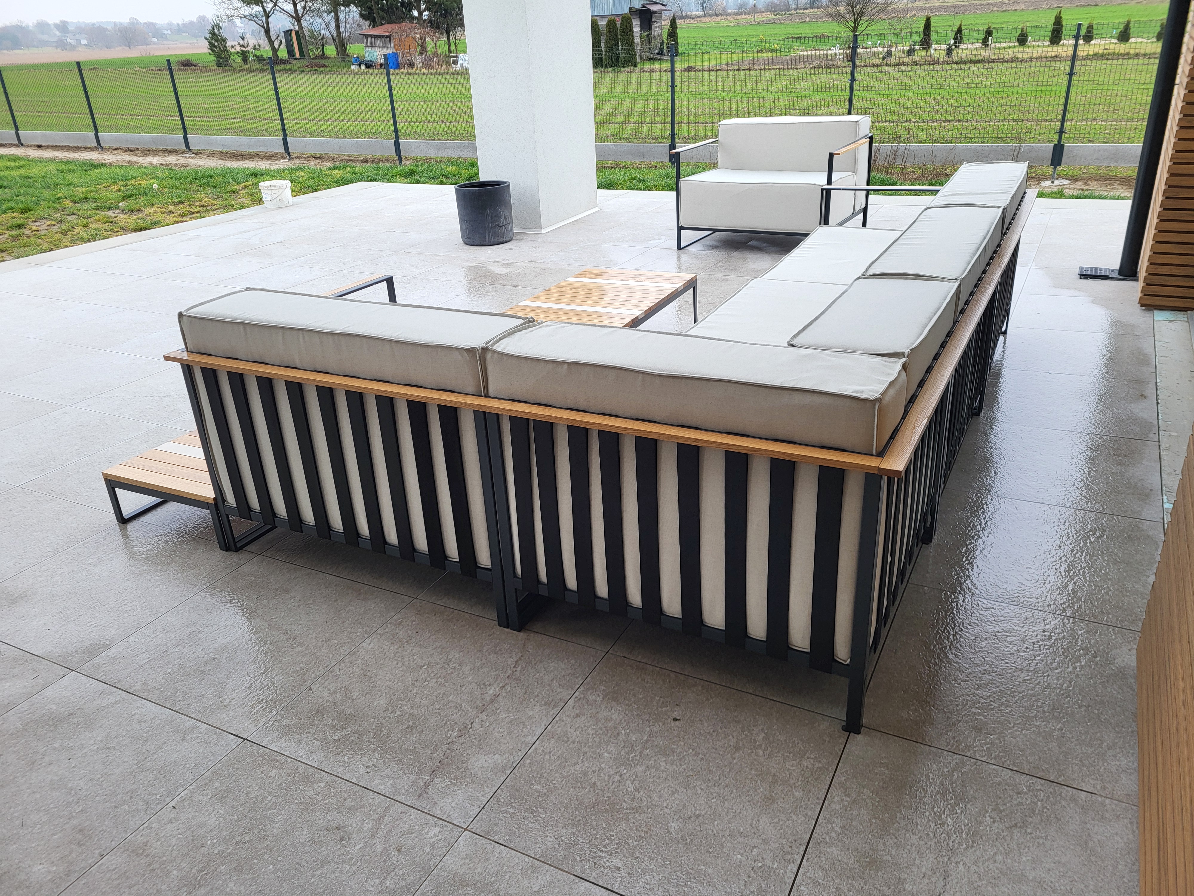 Narożnik tarasowy z jasnymi poduchami i czarną ramą